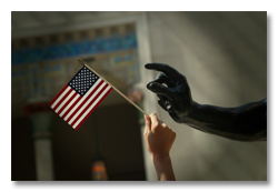 Hand holding small American flag reaching out to hand of marble statue