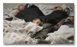 Children sleeping under Rec Cross blankets at border