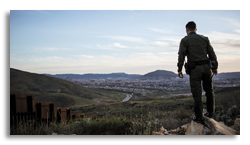 Border patrol officer surveying town from nearby hill